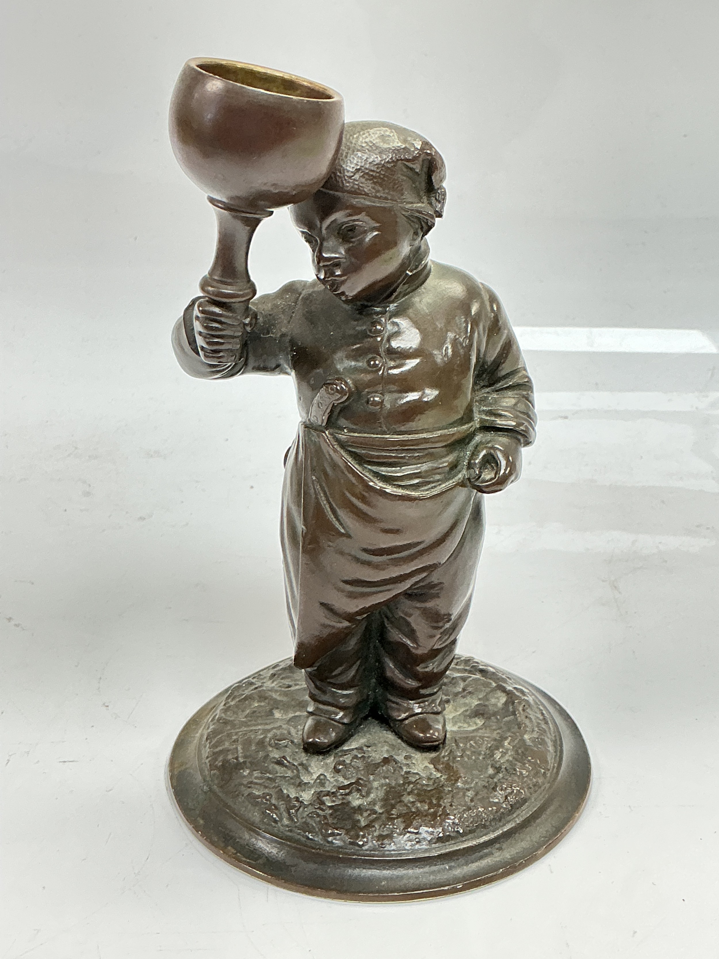 A small bronze figural candlestick of a late 19th Century tradesman, approx height 15cm.