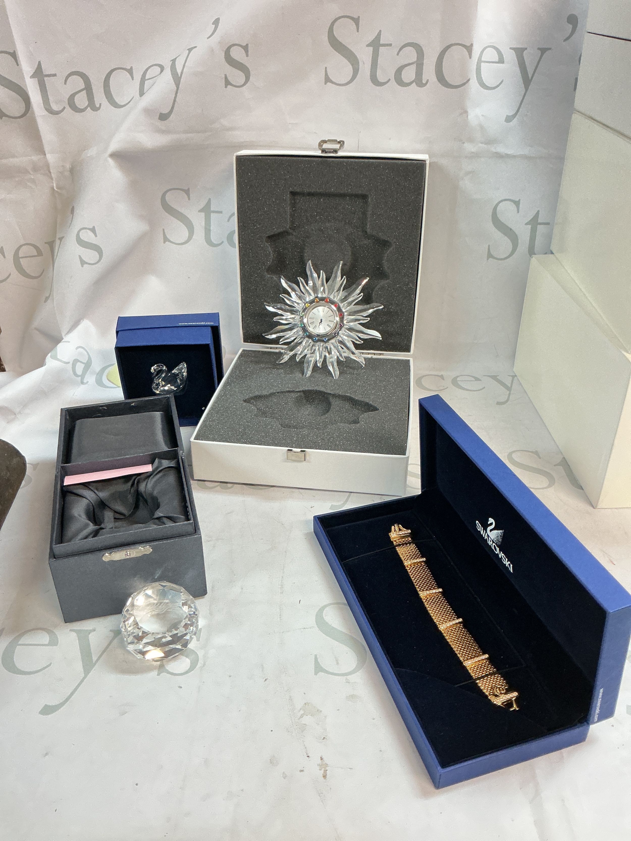A collection of a Swarovski clock, bracelet, swan, and a Hong Kong paperweight 