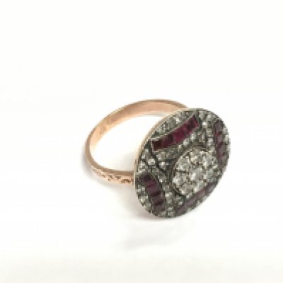 An unhallmarked rose gold silver topped circular A Deco style ring set with calibre cut rubies and BC diamonds with patterned shoulders. Diamonds approx 0.90ct, rubies approx 0.75ct. Approx 6.3g and approx size N. Shipping category A.
