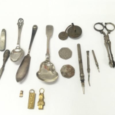 A collective lot including Georgian sugar tongs silver spoons penny fathering made from coins etc.