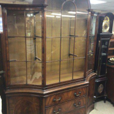 A quality mahogany display cabinet of George III design with an arched top inverted sides glass shelf&rsquo;s above three drawers flanked by cupboards. Height 225cm width 180cm no key. Good condition.