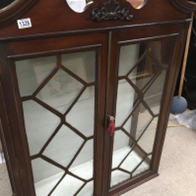 A mahogany display cabinet the swan neck pediment above a pair of glazed doors.