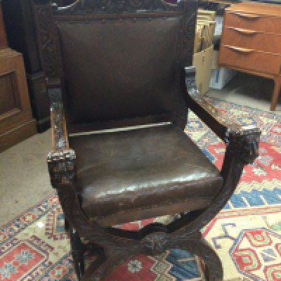 A carved oak open arm chair the arm ends carved with lion heads.