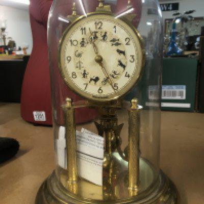 A regulating anniversary clock under a dome