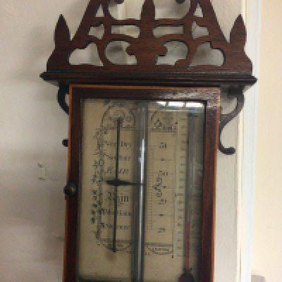 A stick barometer with a pierced applied pediment with Mercury tube on a mahogany back board with cross banded satin wood edge the paper dial with thermometer and maker Samual Lainton Halifax the tube full and functional.