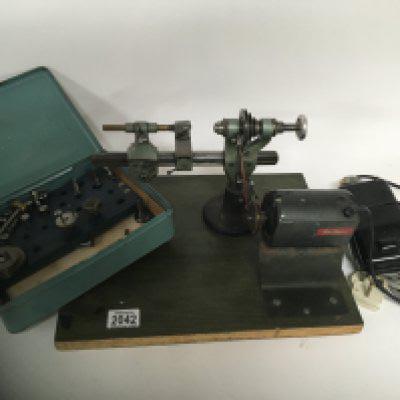 A watchmakers table top electric lathe with some attachments and accessories.