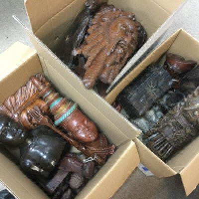 Three boxes of carved wooden items comprising mainly tribal masks. Shipping category D.