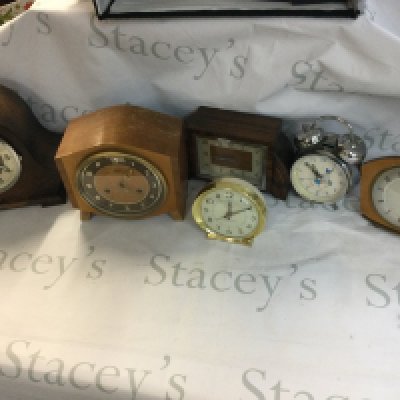 A collection of clocks including mantle clocks and alarm clocks.
