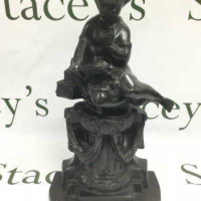 A bronze figure of a cherub seated amongst various books and raised on a column, approx height 35.5cm. Shipping category D.
