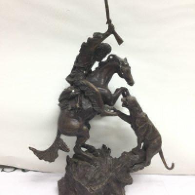 A bronzed figure of a warrior on horseback in combat with a cougar or jaguar, approx total height 41.5cm. Shipping category D.