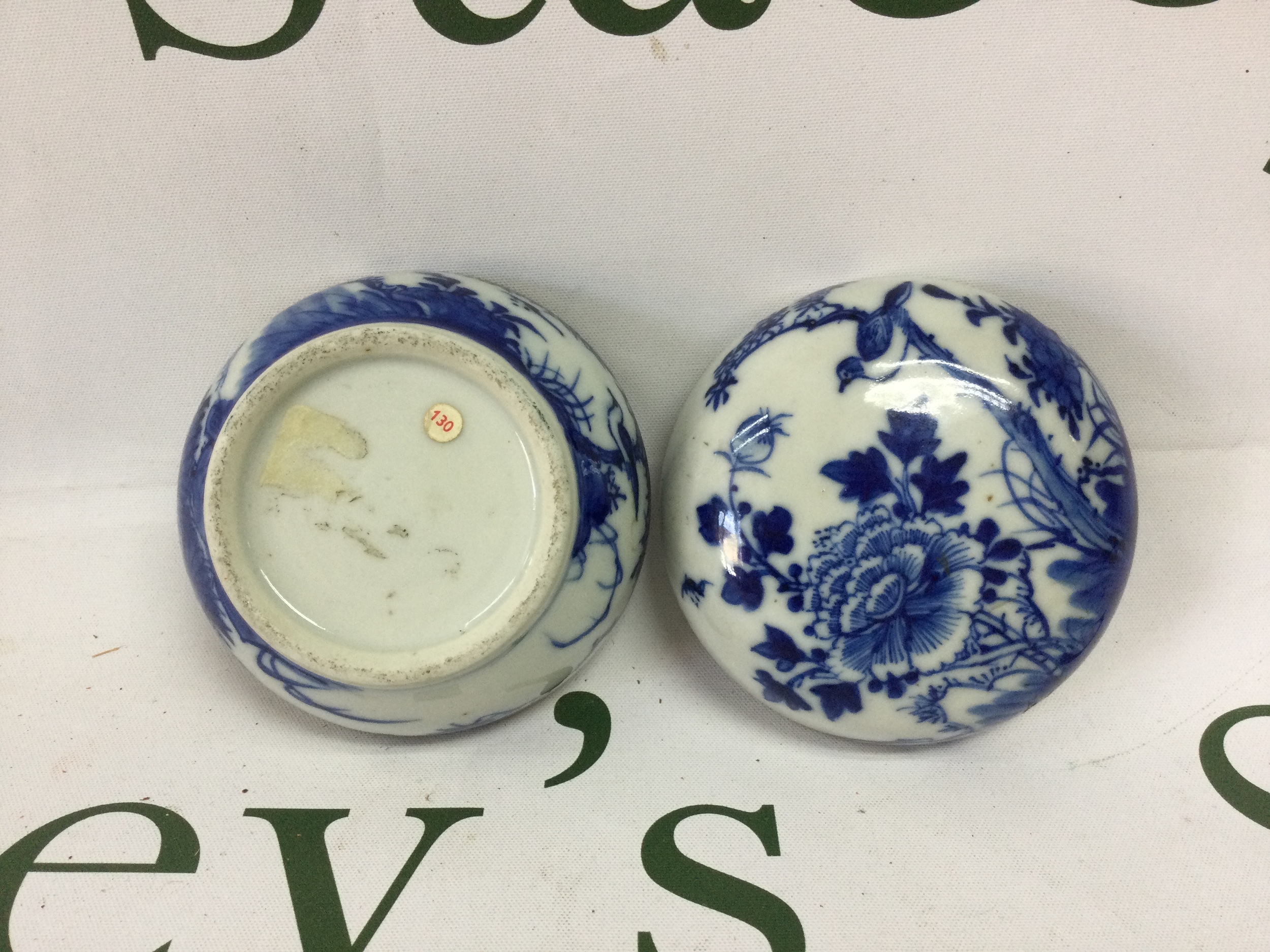 Three 18/19th C Chinese blue and white lidded pots, largest 55mm x 85mm decorated with birds and flowers and old stock label to base "130" in red, smooth rounded base no damage. Blue and white cylinder lidded pot depicting scholar and lamp holder to the top, with seated scholars around rim of the base, 45 mm x 62mm minor chips to the rim, of both pieces. smallest pot decorated in floral motifs 21mm x 49mm no damage