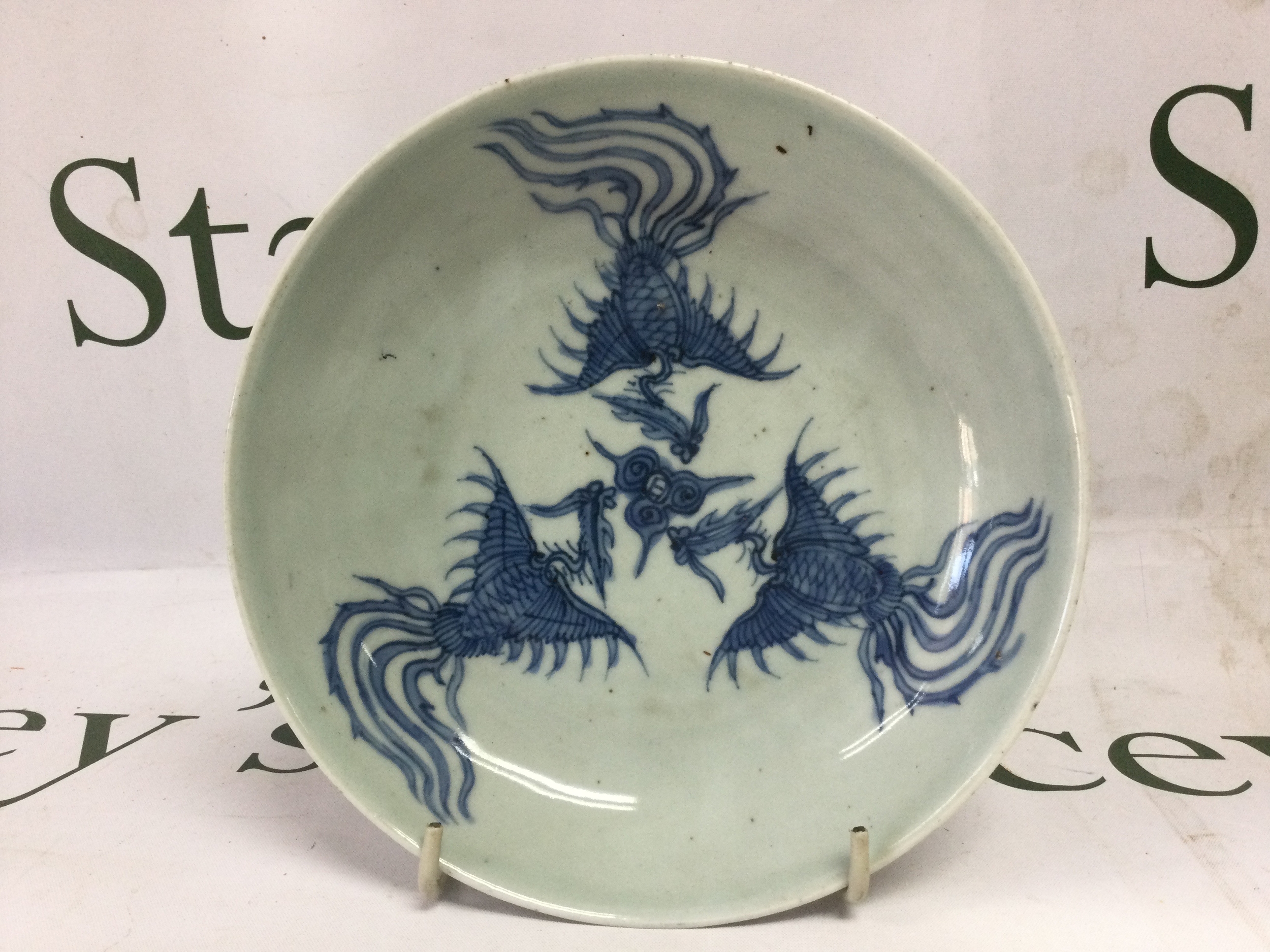 17/18th C Chinese Phoenix plate depicting three Phoenix flying around three central clouds surrounding the sun. Representing feminine virtues, central hand painted character mark to the base, good condition free from any damage some minor firing faults.19.5Cm.