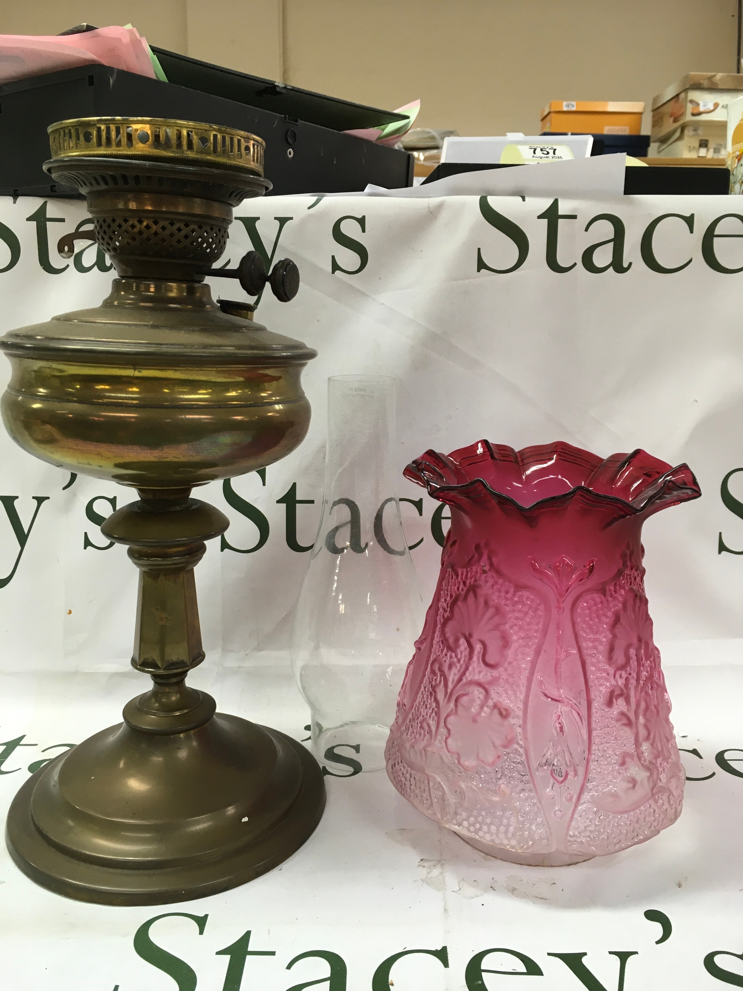 An antique Victorian brass oil lamp featuring a cranberry glass shade. 