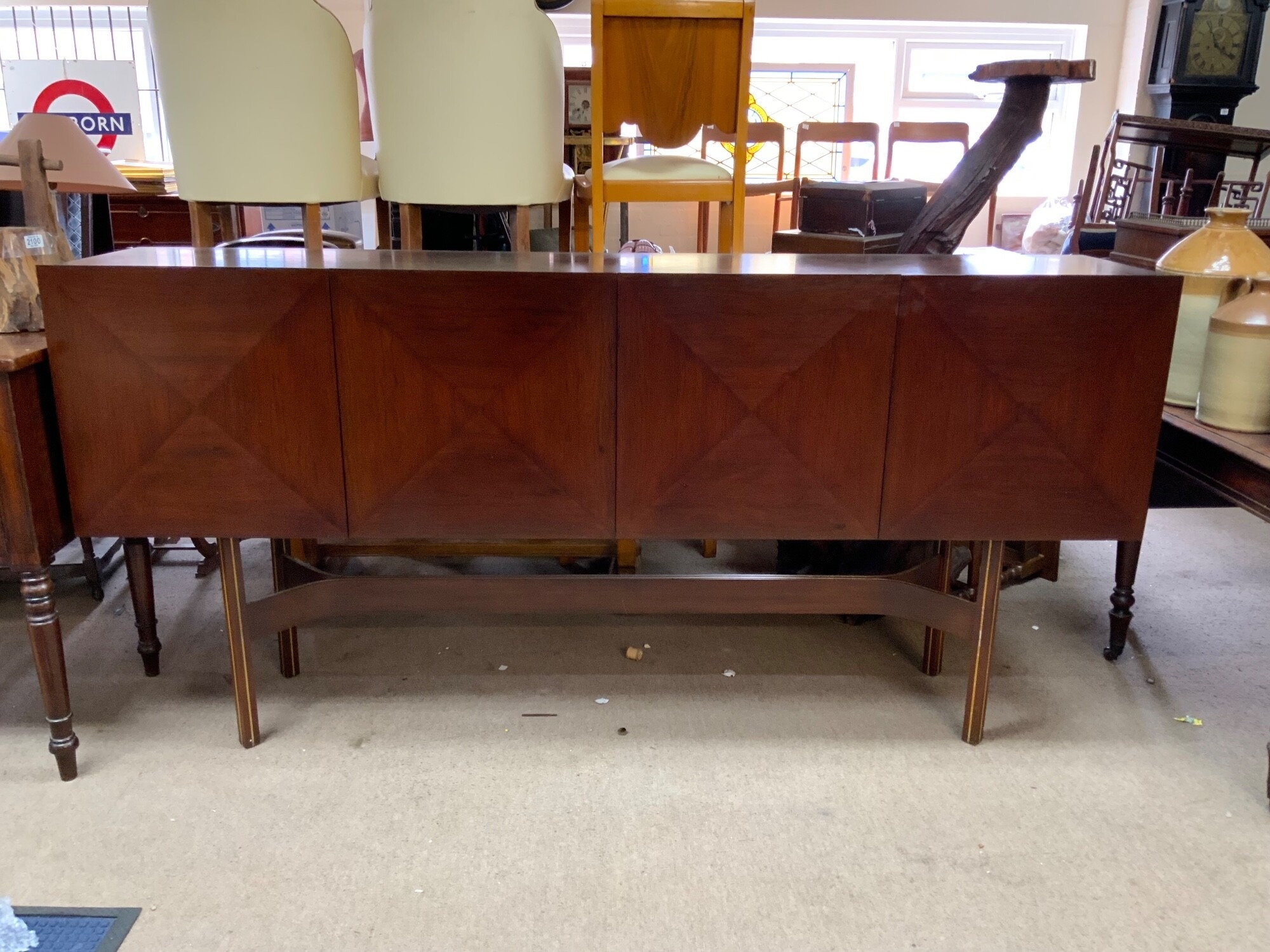 A mid-century dining suite, the sideboard, often called a "Pointe de Diamant" design, features four doors with a distinct sculpted geometric design the legs inlaid with brass strips, the dining rosewood extending dining table with 6 conforming upholstered chairs. Dimensions 221cm x H.107cm x depth 45cm.