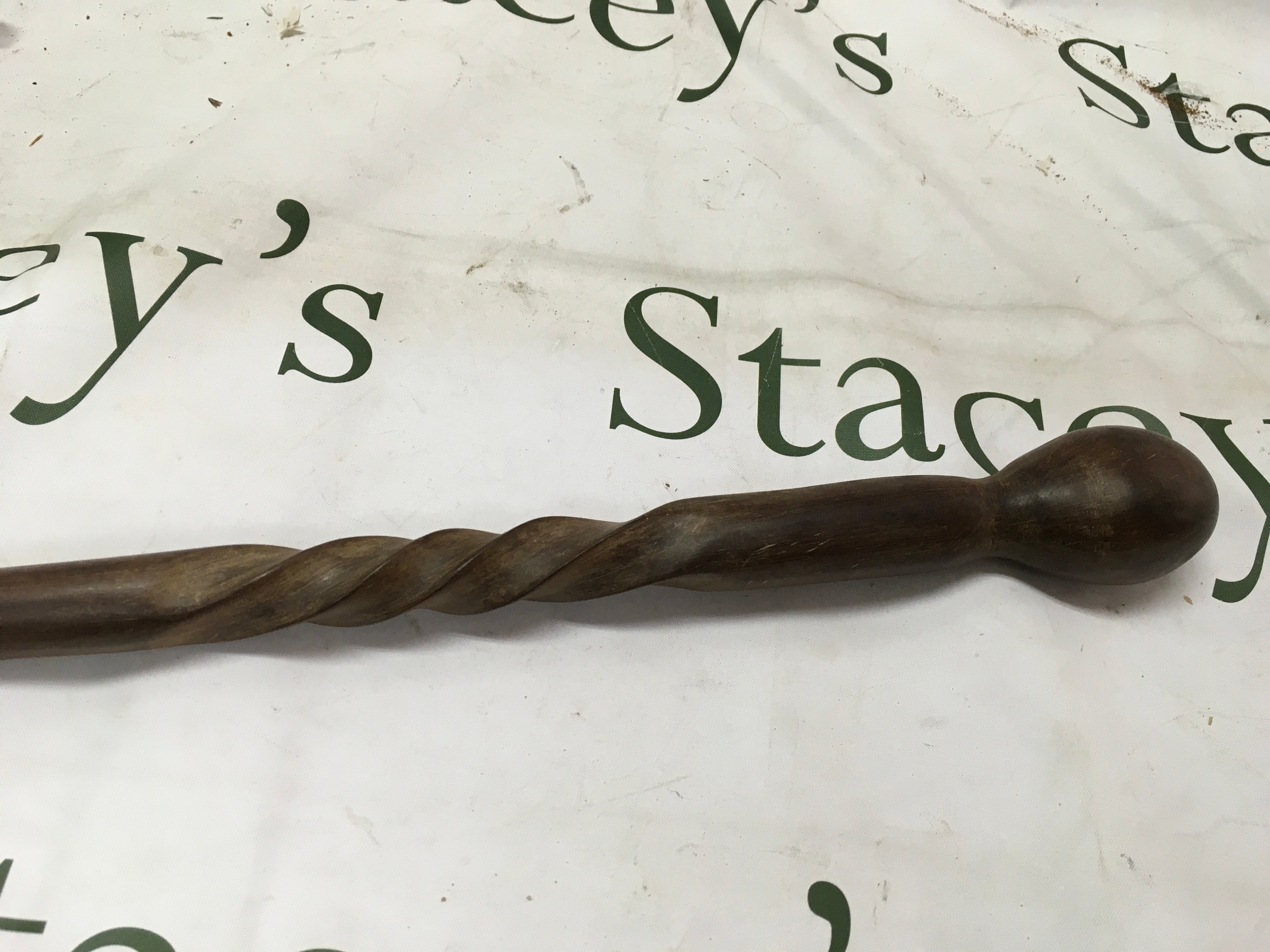 A vintage wooden walking stick featuring a distinct spiraled 'barley twist' design along its shaft and a simple knob handle. 