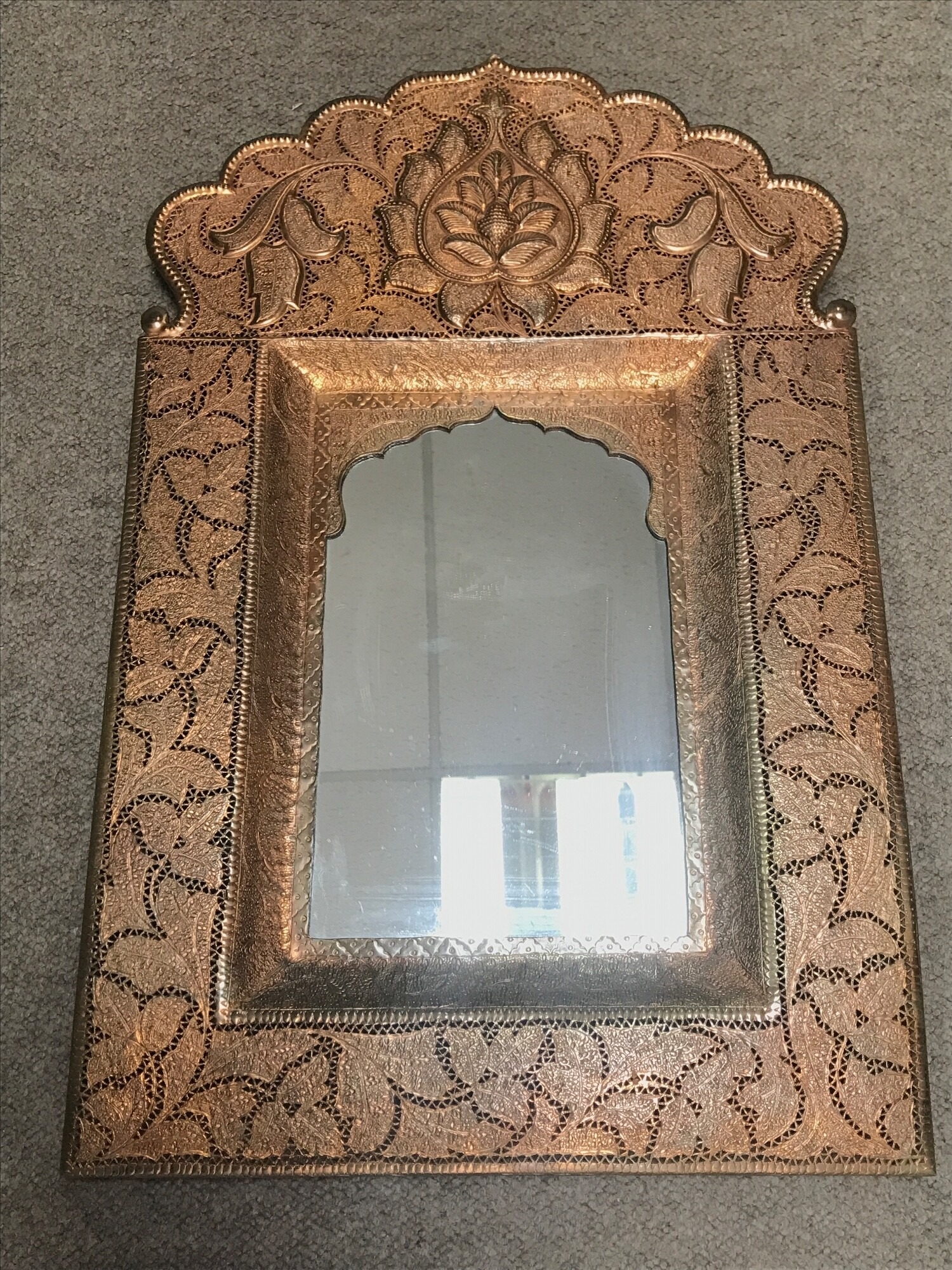 An antique copper wall mirror features elaborate hammered and pierced details in a traditional Indian Jalidar/ Jharokha style frame. Frame size 39cmx60cm NO RESERVE