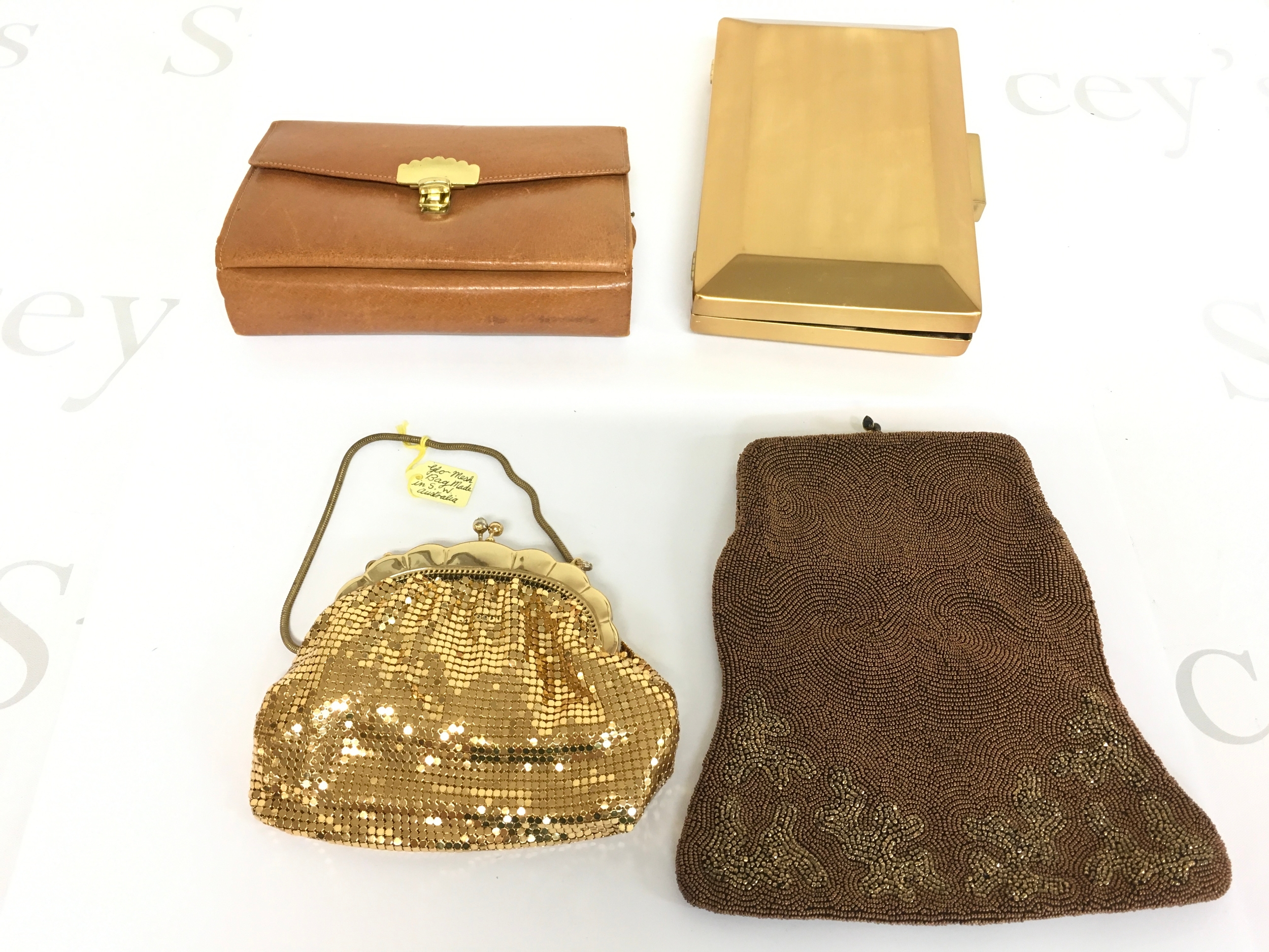 Four bags including a beaded bag, leather clutch bag, glo mesh bag made in S W Australia and an unusual metal John Lewis bag.
