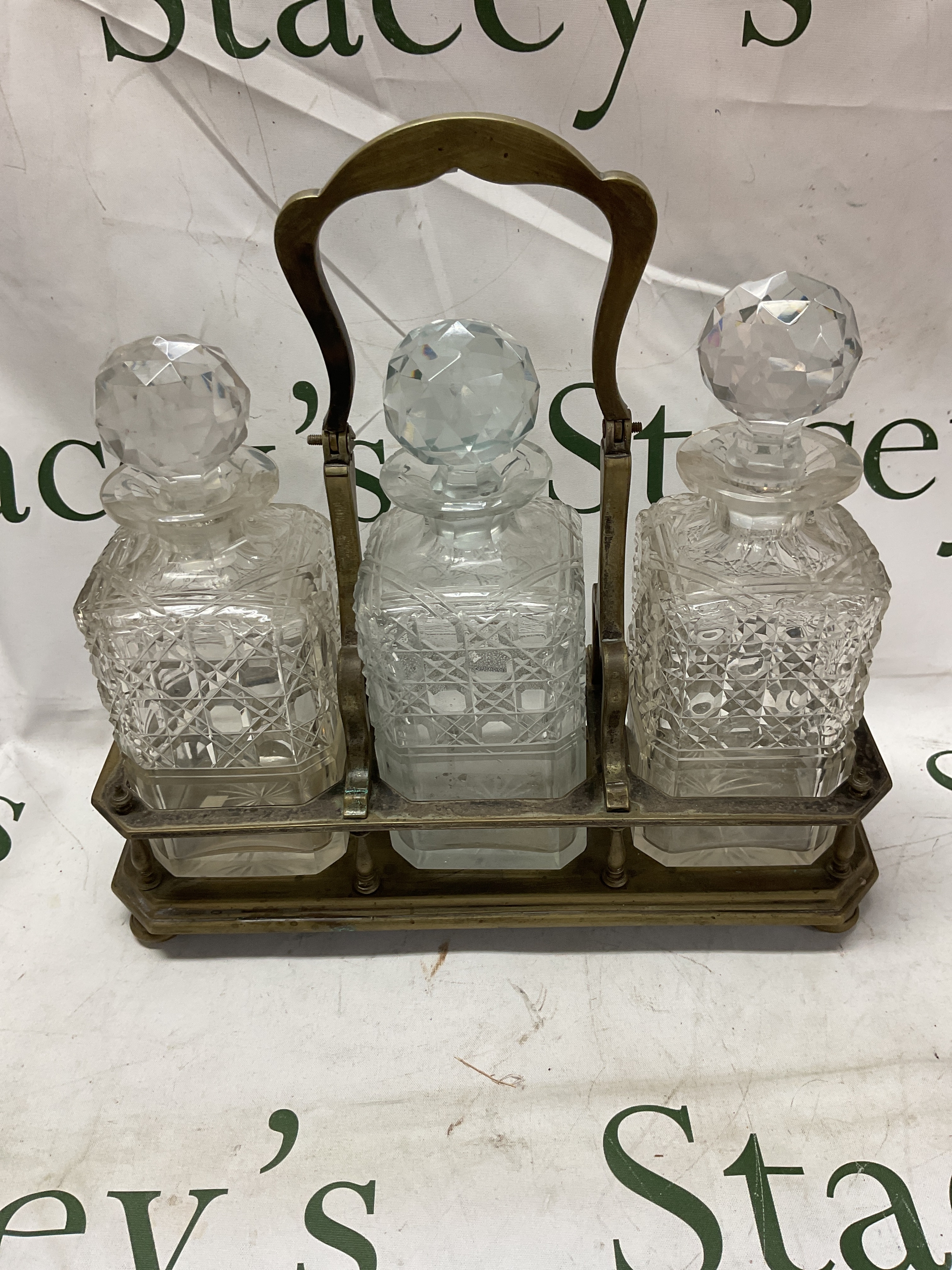 19th C tantalus style decanter holder. With three original decanters with hobnail cut and stars to the base. 32 cm H 32cm W.