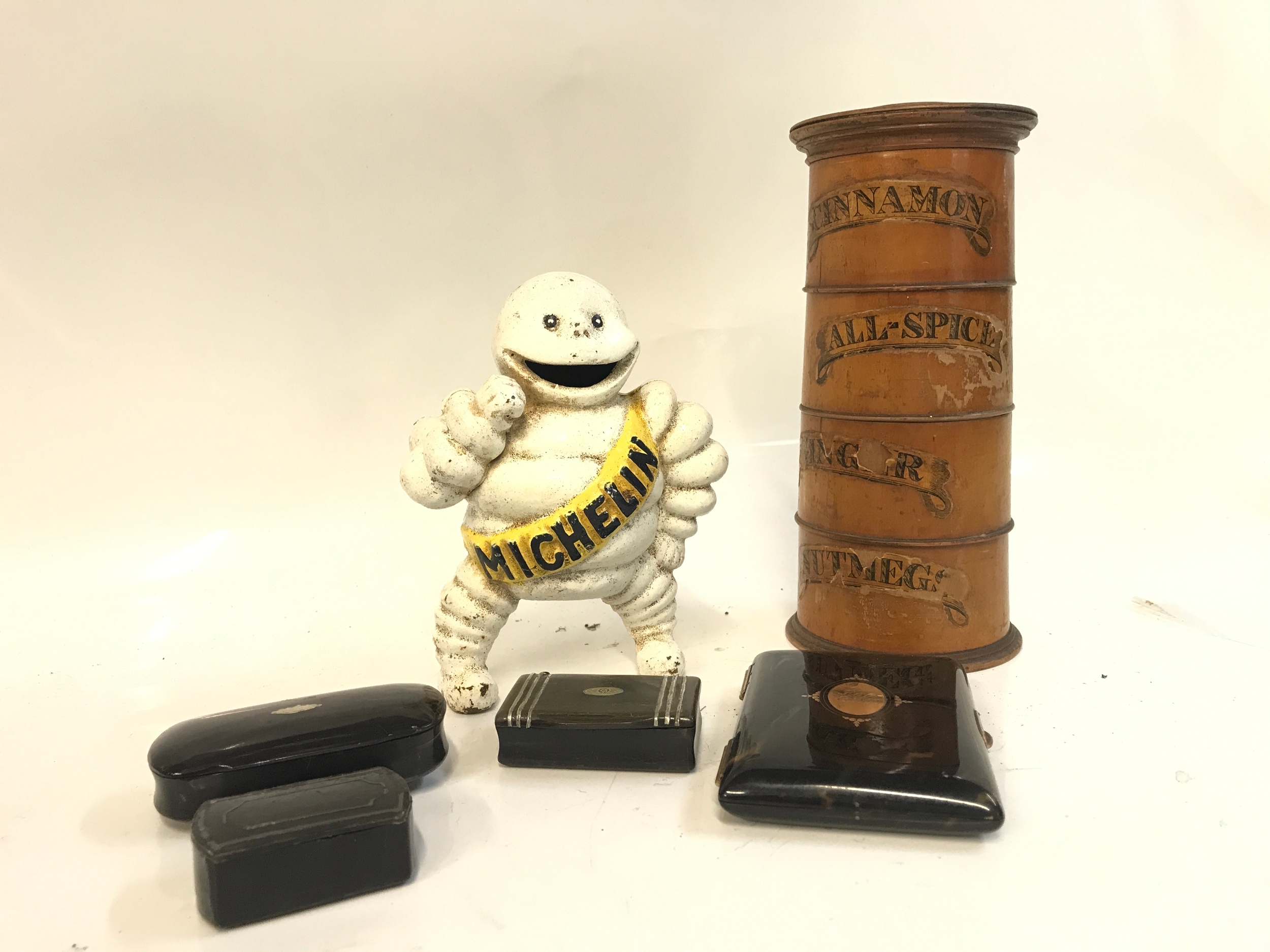 A Michelin man cast iron money box, four snuff boxes, treen spice tower 