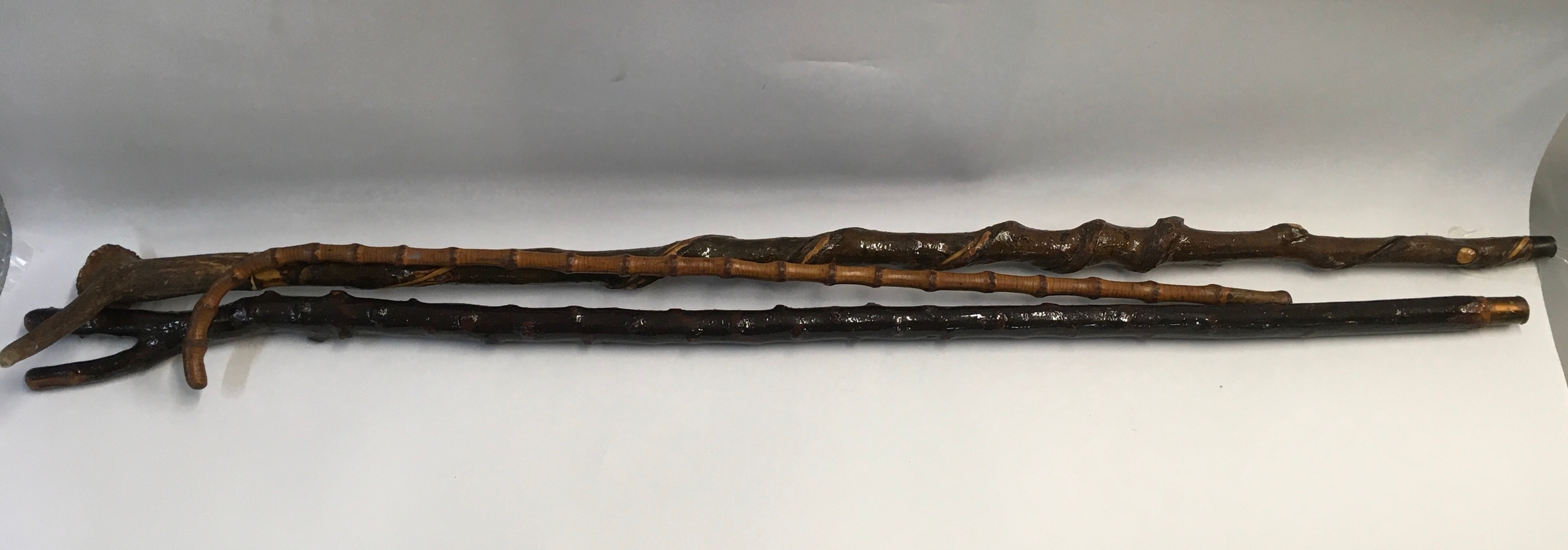 A collection of three distinct traditional wooden walking sticks 