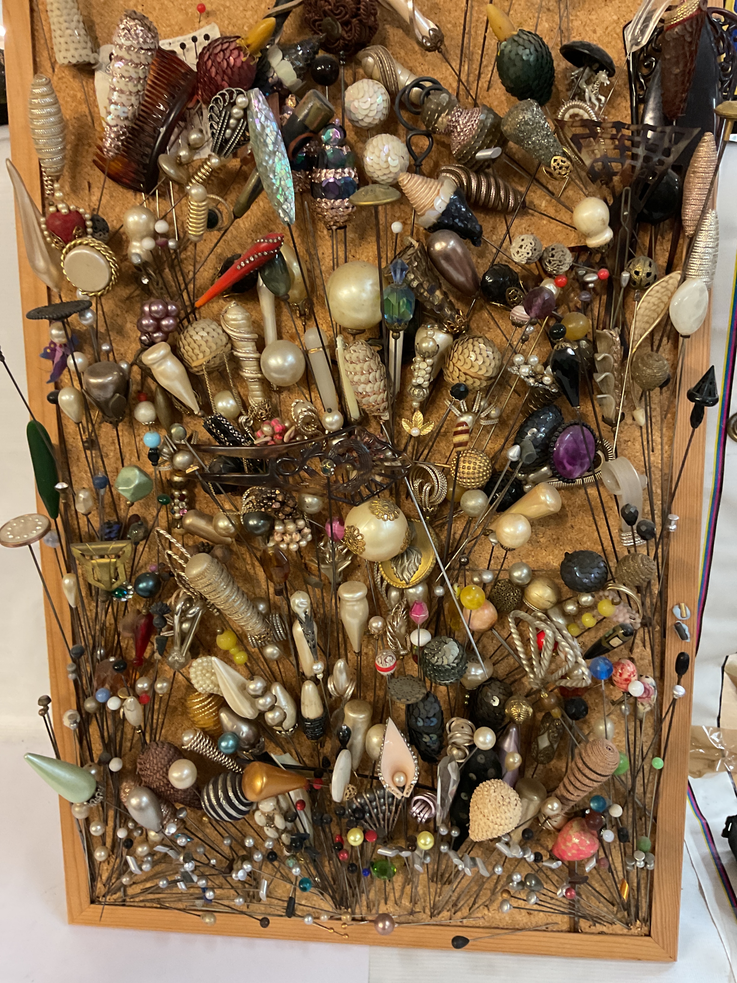 Large collection of hat pins in cork board to inc silver and military examples.