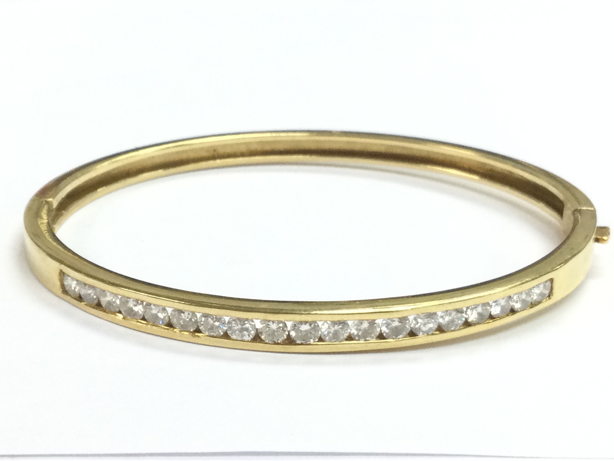 A 18ct gold bangle set with a row of diamonds, 17.3g, 6.5Cm wide 