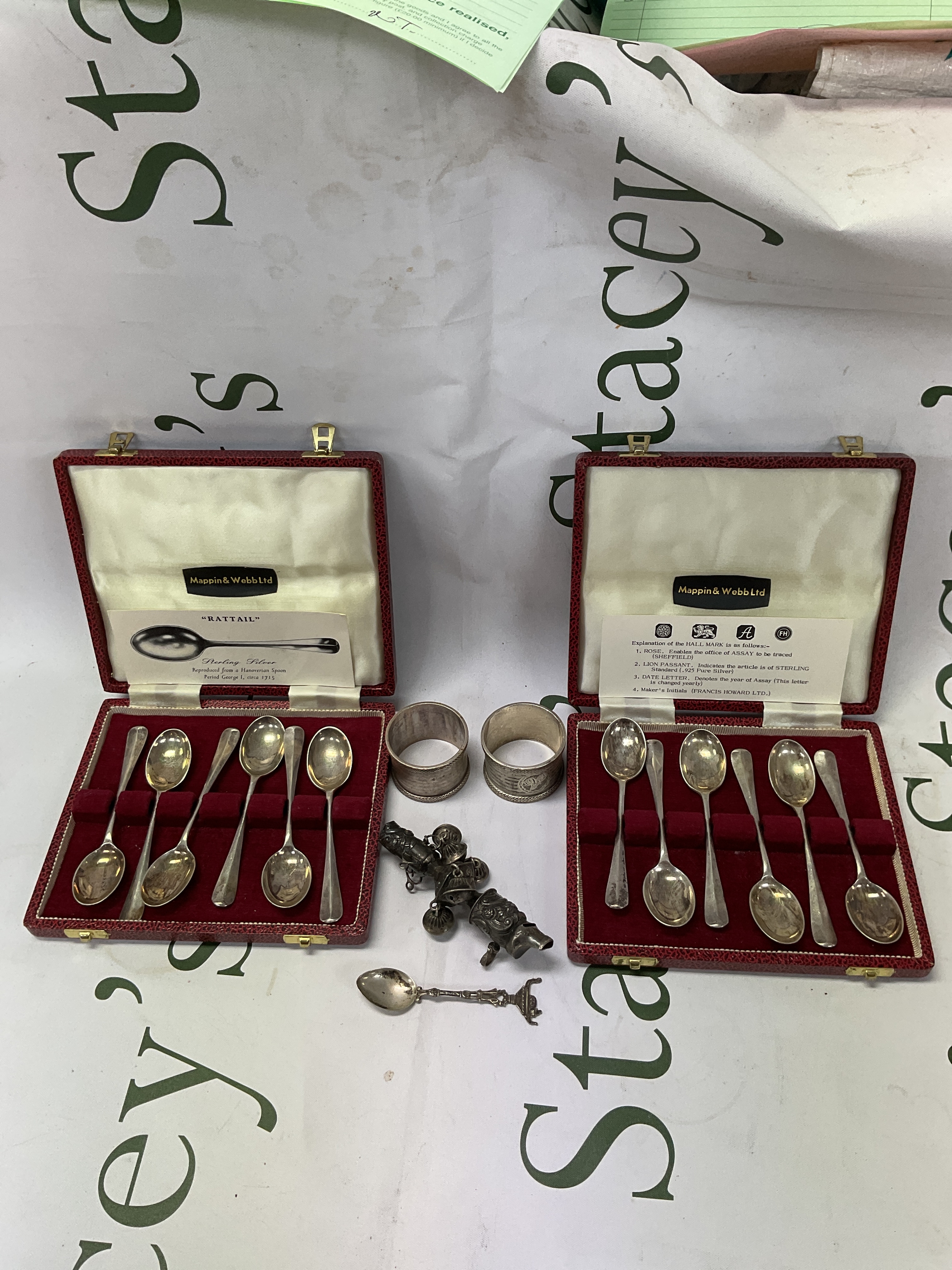 Two cased sets of 1977 jubilee hallmarked rat tail tea spoons by Mappin and Webb, two silver napkin rings and a silver rattle. Weight.280 grams.