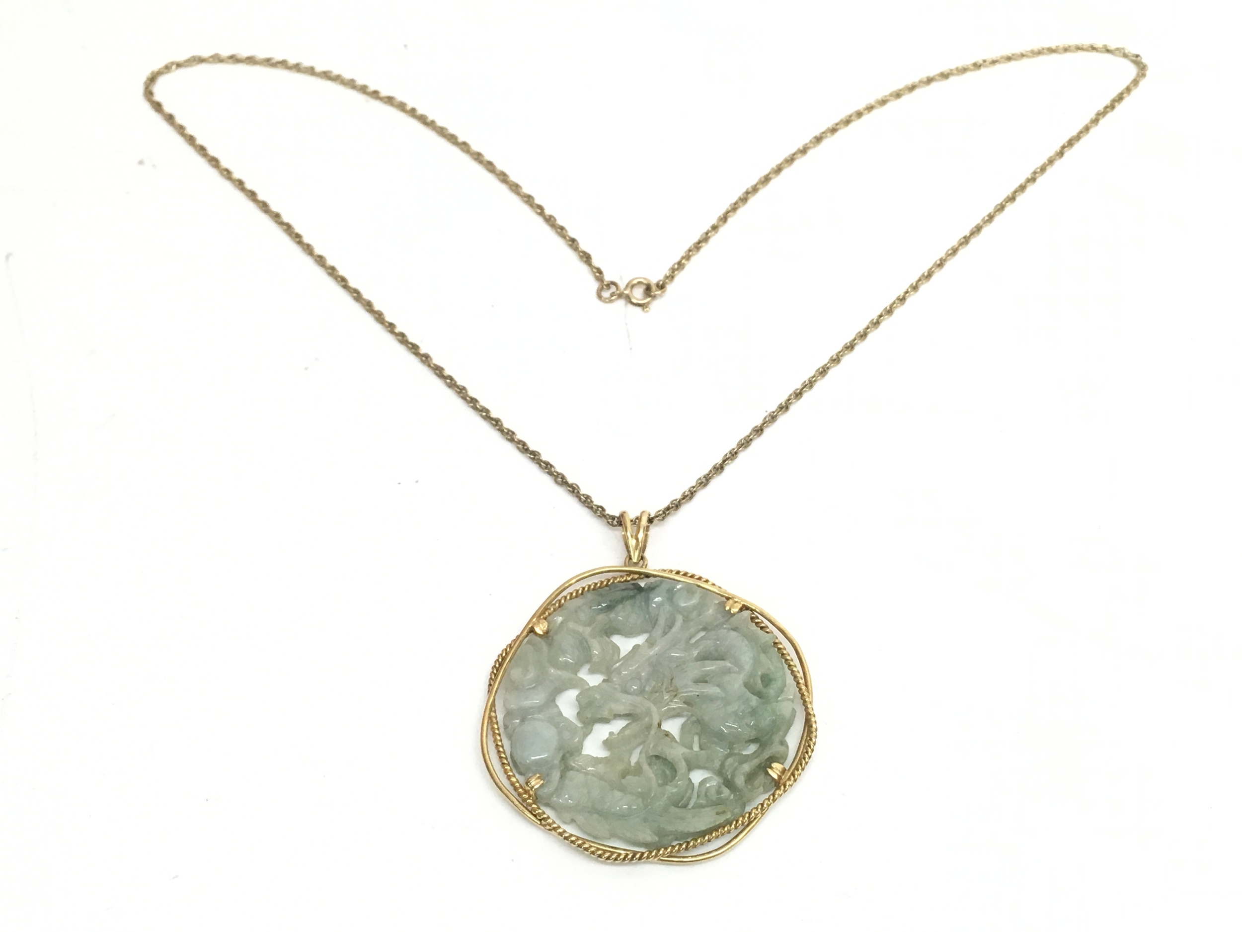 A Chinese 14ct gold mounted jade dragon pendant on a 9ct gold chain (30cm long). 27.5g total weight
