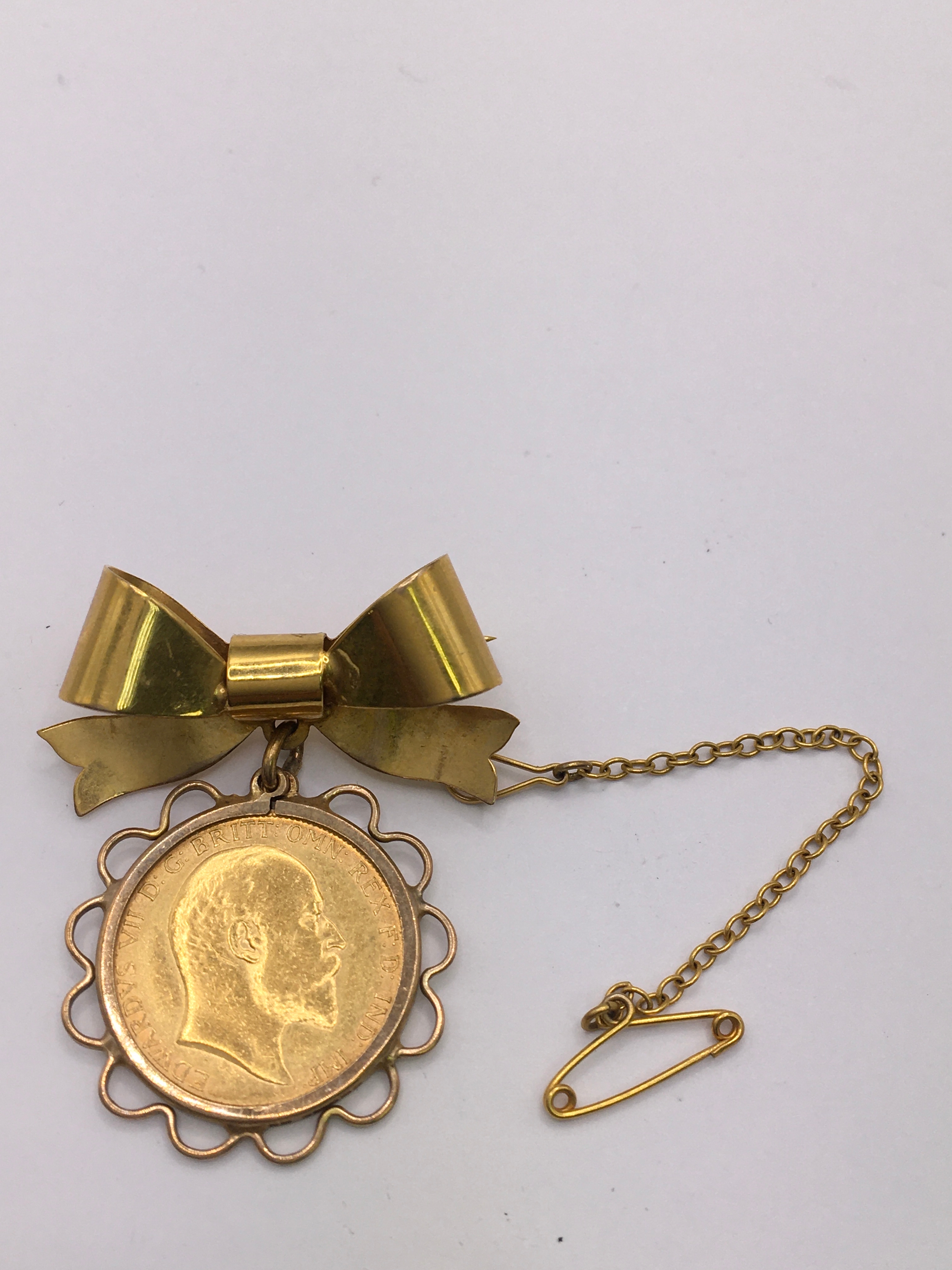 A 9ct yellow gold bow brooch set with a 1910 half sovereign. Approx W2 x L3.5cm 