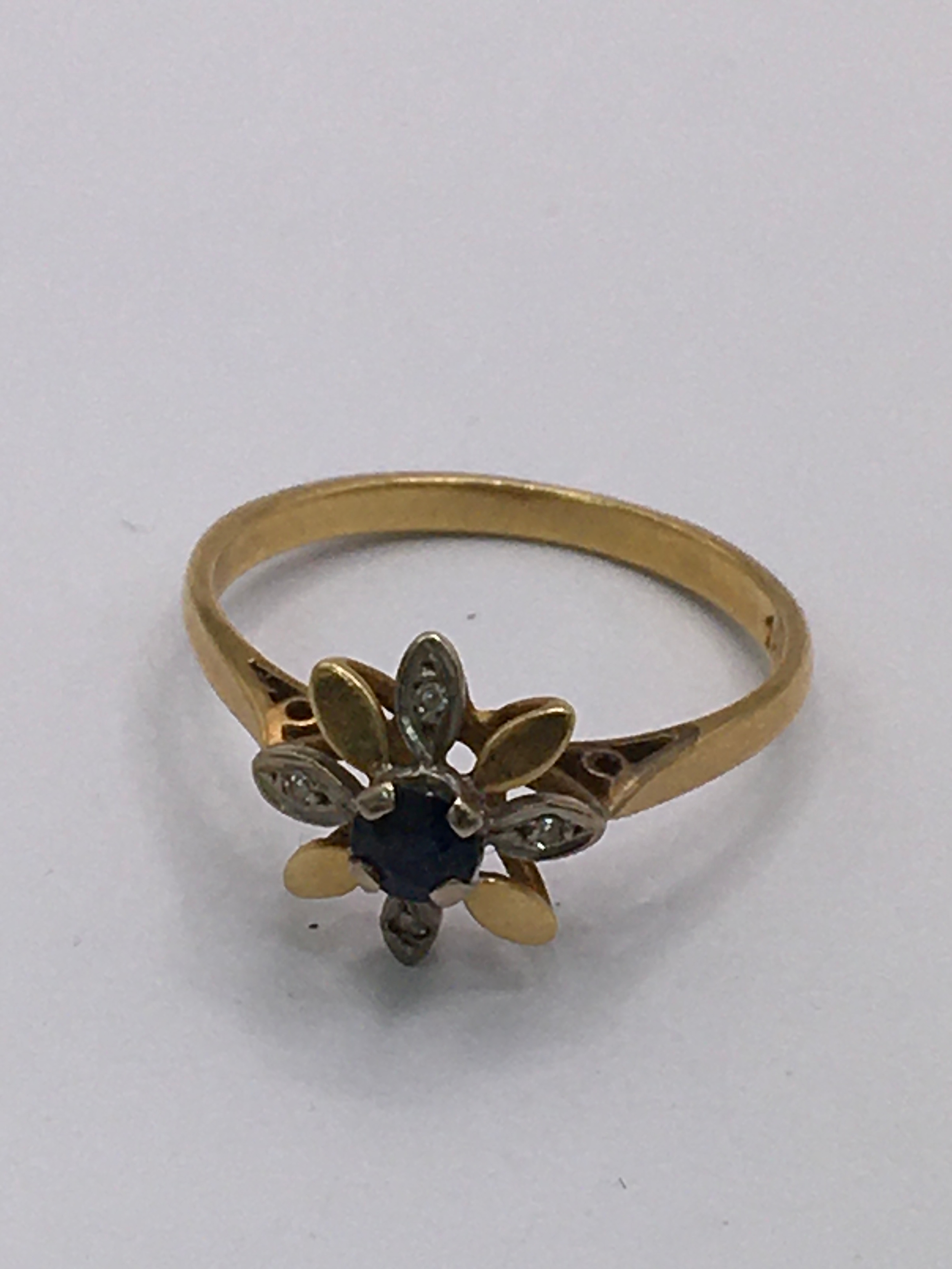 An 18ct gold ring of flower shaped design, set with small sapphire and chip stones