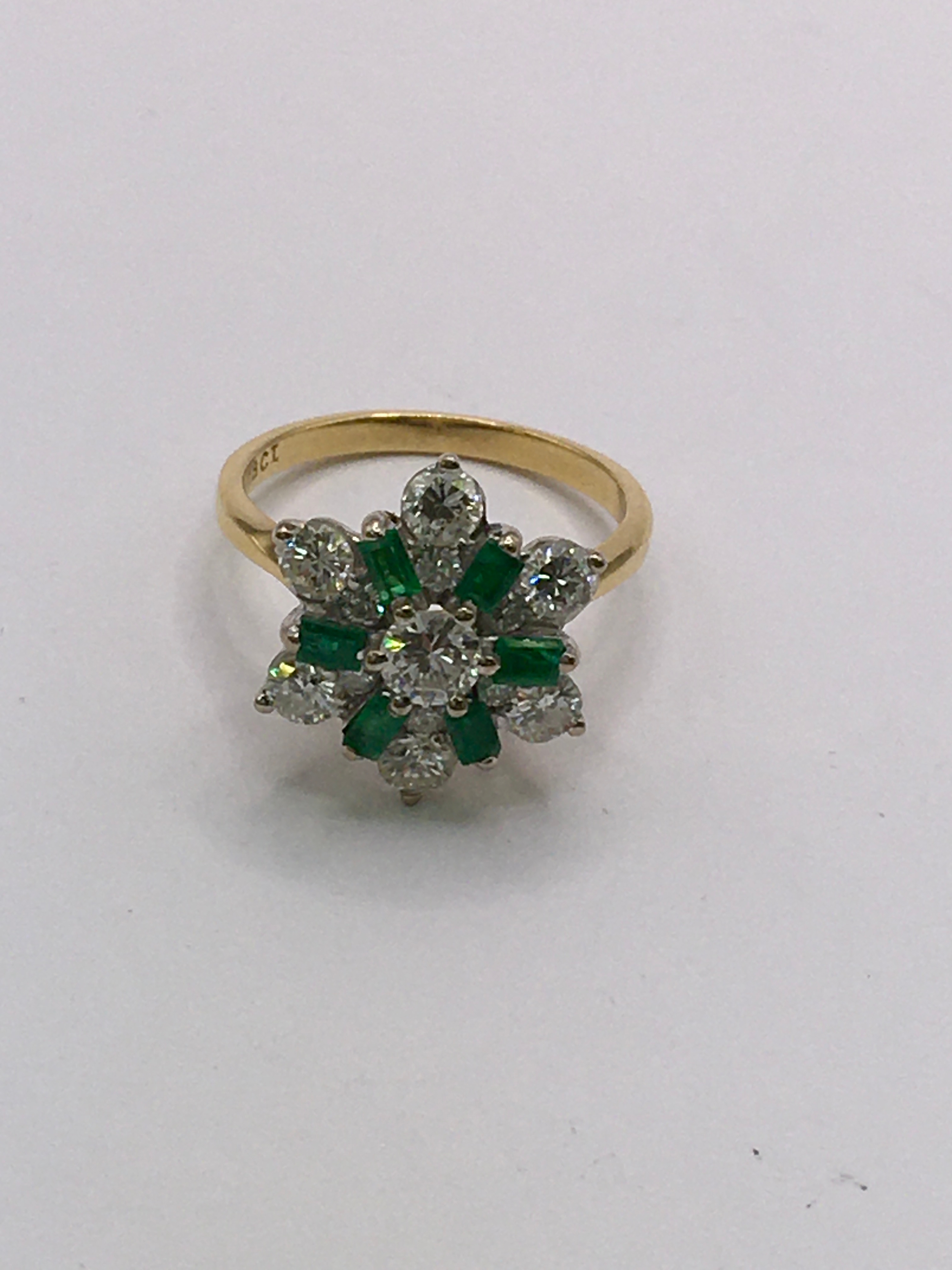 An 18ct gold ring of flower design, set with baguette cut emeralds and brilliant cut diamonds. Size M
 