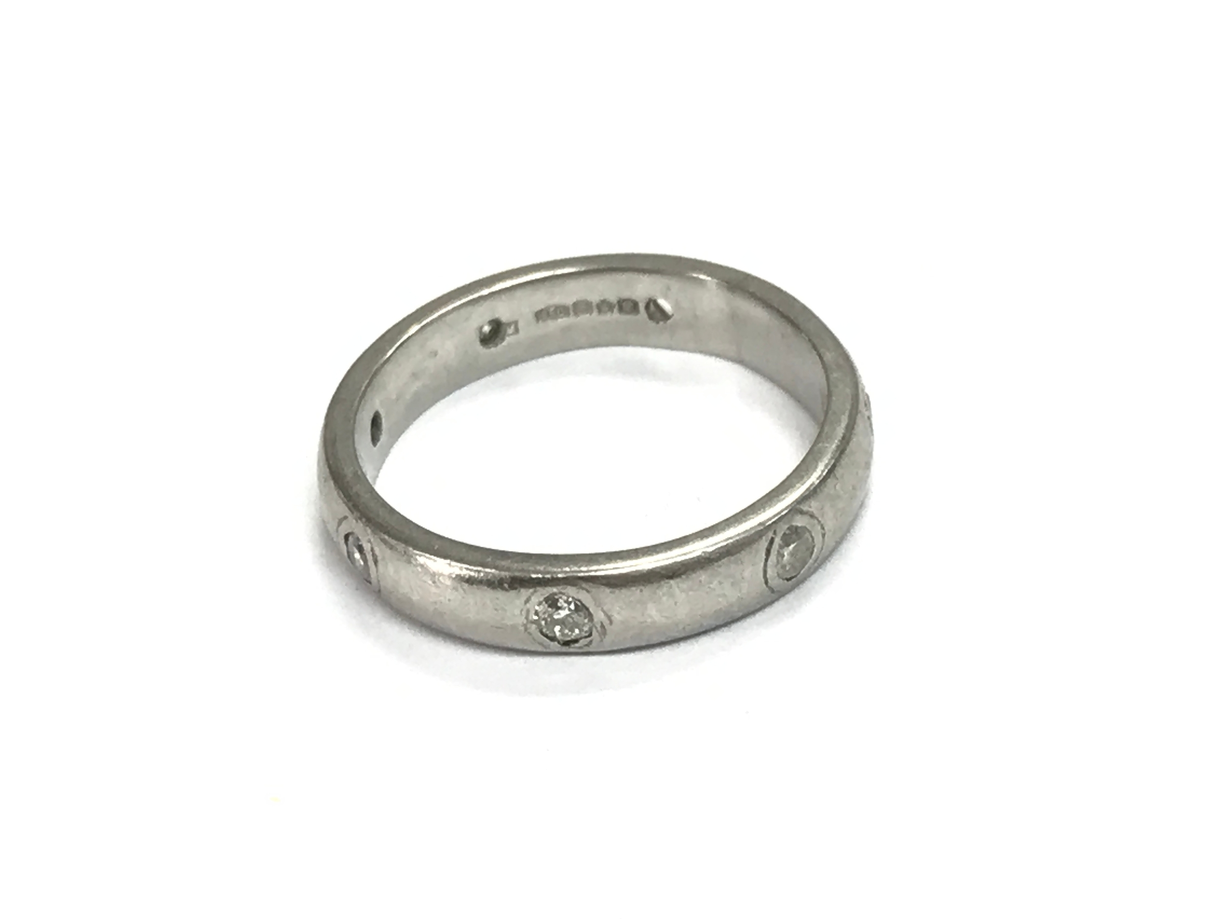 A platinum eternity band set with diamonds (one missing). Size L and 6.2g
