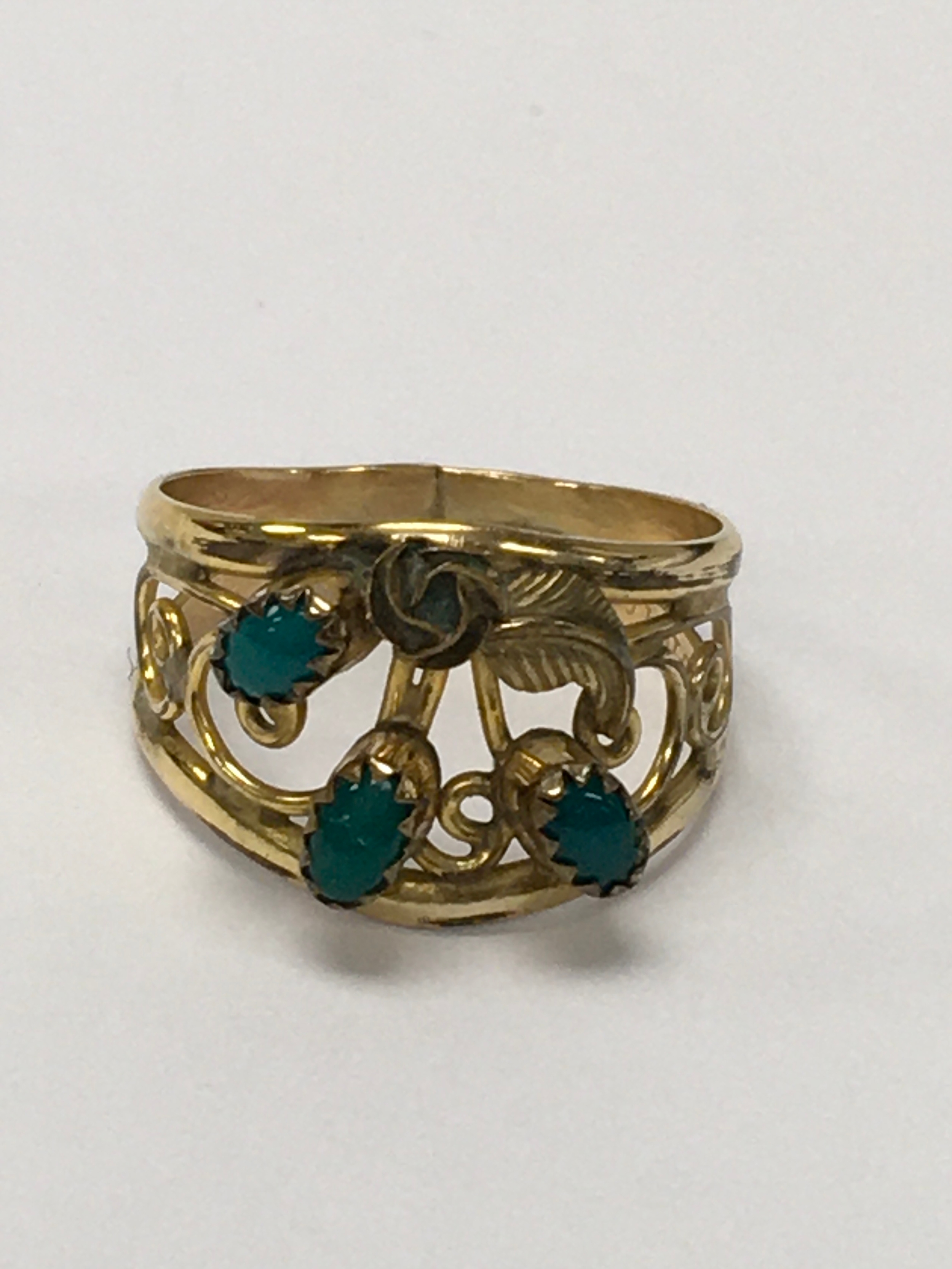 A 12kt, 1/20 gold filled field ring, of scroll design set with three cabouchon green stones. Approx size r.