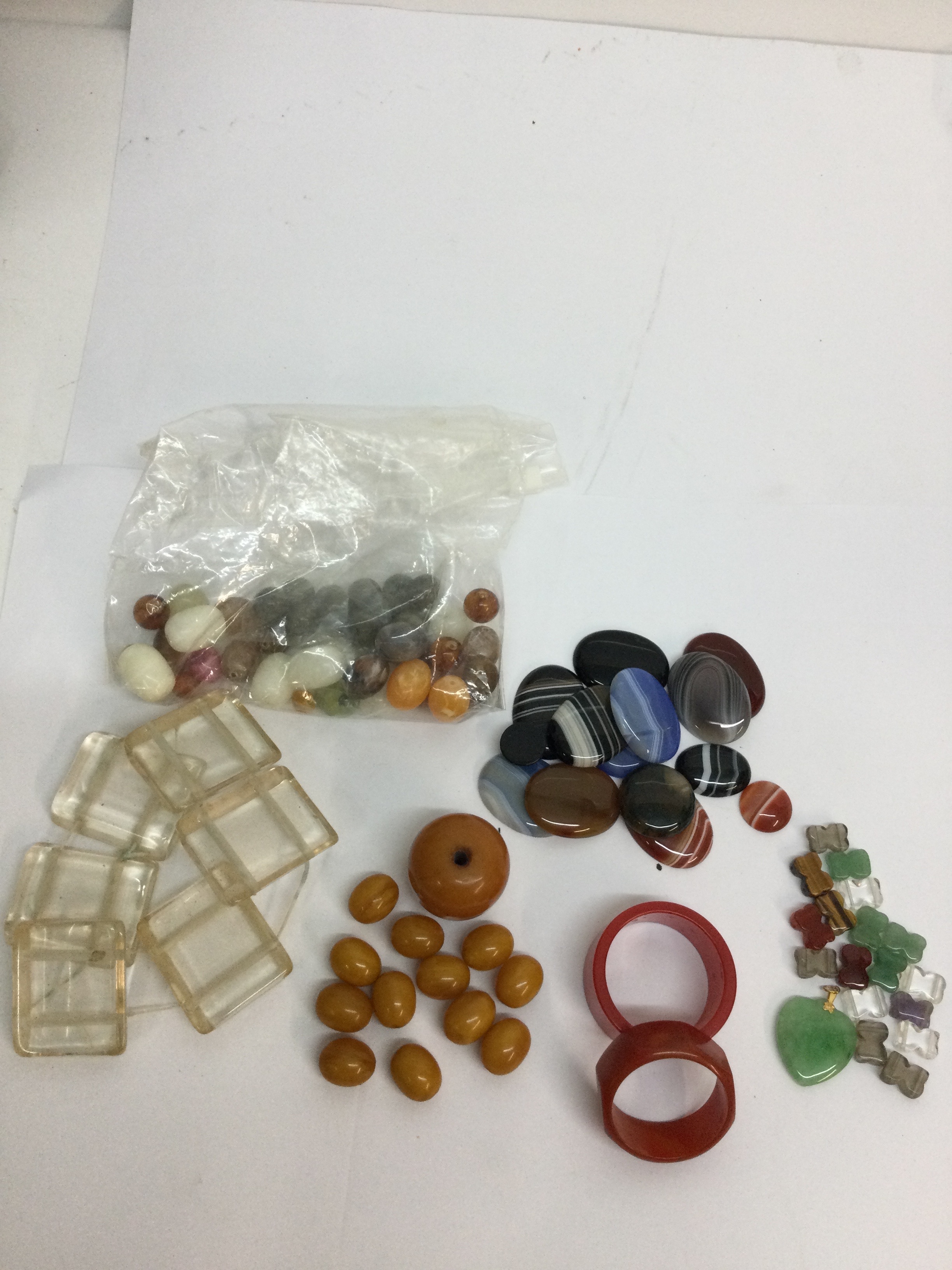 A small group of amber coloured early plastic beads, two Bakelite napkin rings, plus polished hardstone examples