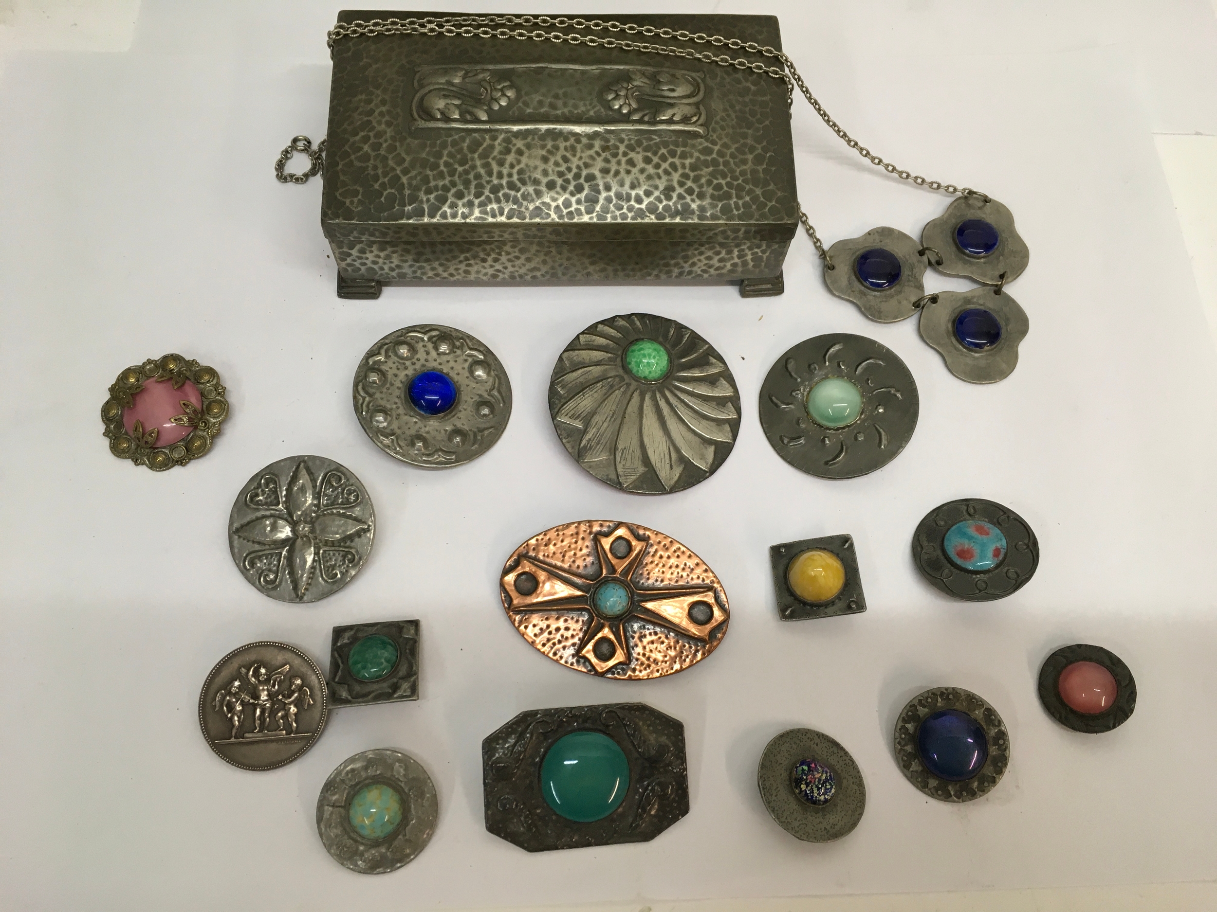 An Arts and Crafts pewter box containing pewter, stone set cabochon brooches