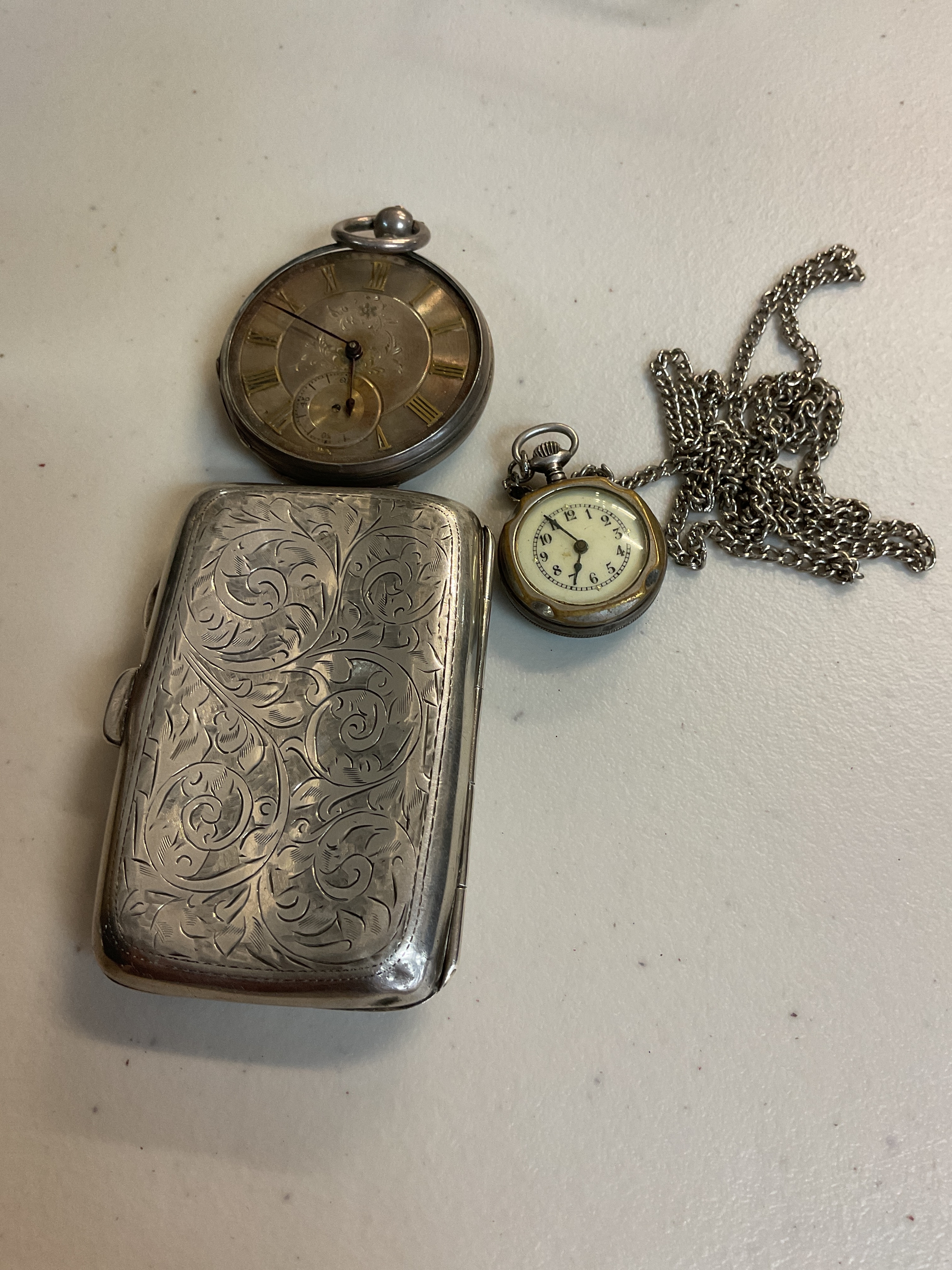 A collection of silver including a silver cigarette case and two silver pocket watches. 