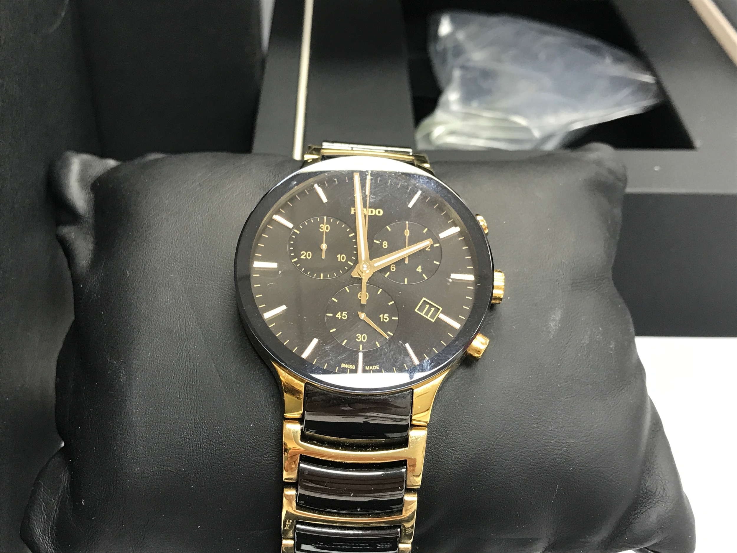 Rado Centrix Chronograph watch featuring a striking black dial with yellow gold plated PVD accents and a two-tone ceramic and gold-plated bracelet. Comes with box, card and manual.