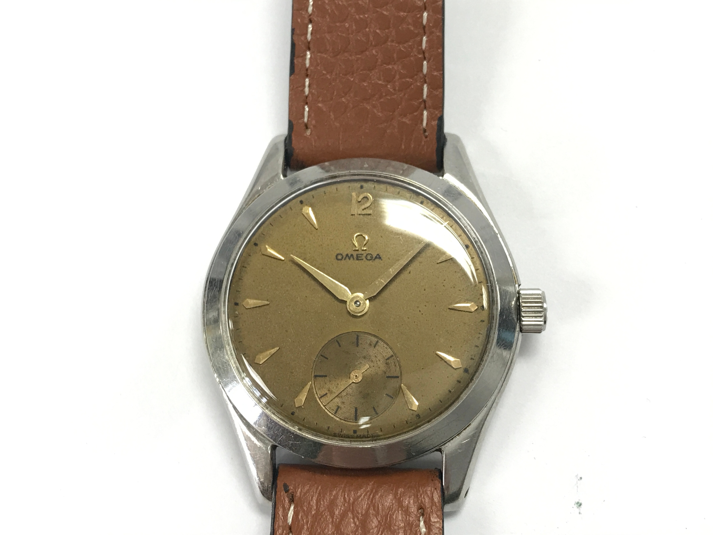 vintage Omega with aged golden dial featuring a classic small-seconds sub-dial. On aftermarket brown leather strap.