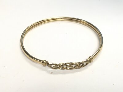 A 9ct gold bangle with a Celtic pattern clasp. Approx weight 4 grams.