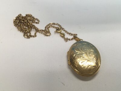 A 9ct gold scroll pattern locket with a diamond cut belcher chain. Approx weight 10.8 grams.