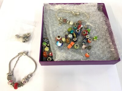 A collection of silver charms brackets and assorted beads.