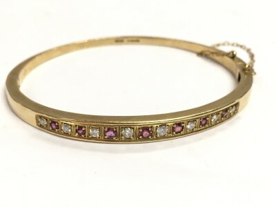 A 9ct gold bangle ruby and diamond set. 13.9g total weight. 6.5cm wide