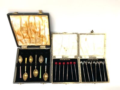 A cased set of 6 hallmarked silver and enamel teaspoons together with 2 boxed sets of 6 cocktail sticks.