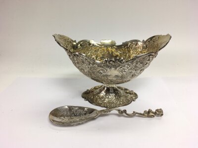 A shaped silver dish with elaborate scrollwork and floral decoration and a silver piercework spoon, both with London hallmarks, approx width of dish 7cm, approx total weight 300g.