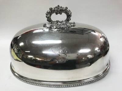 An old Sheffield plate venison dish cover. The dome is adorned with a gadrooned border along the lower edge and a detailed, leaf-capped handle And tinned interior. Engraved with a baron crest of a griffin. 
Approximately 46cm wide and 25cm tall.