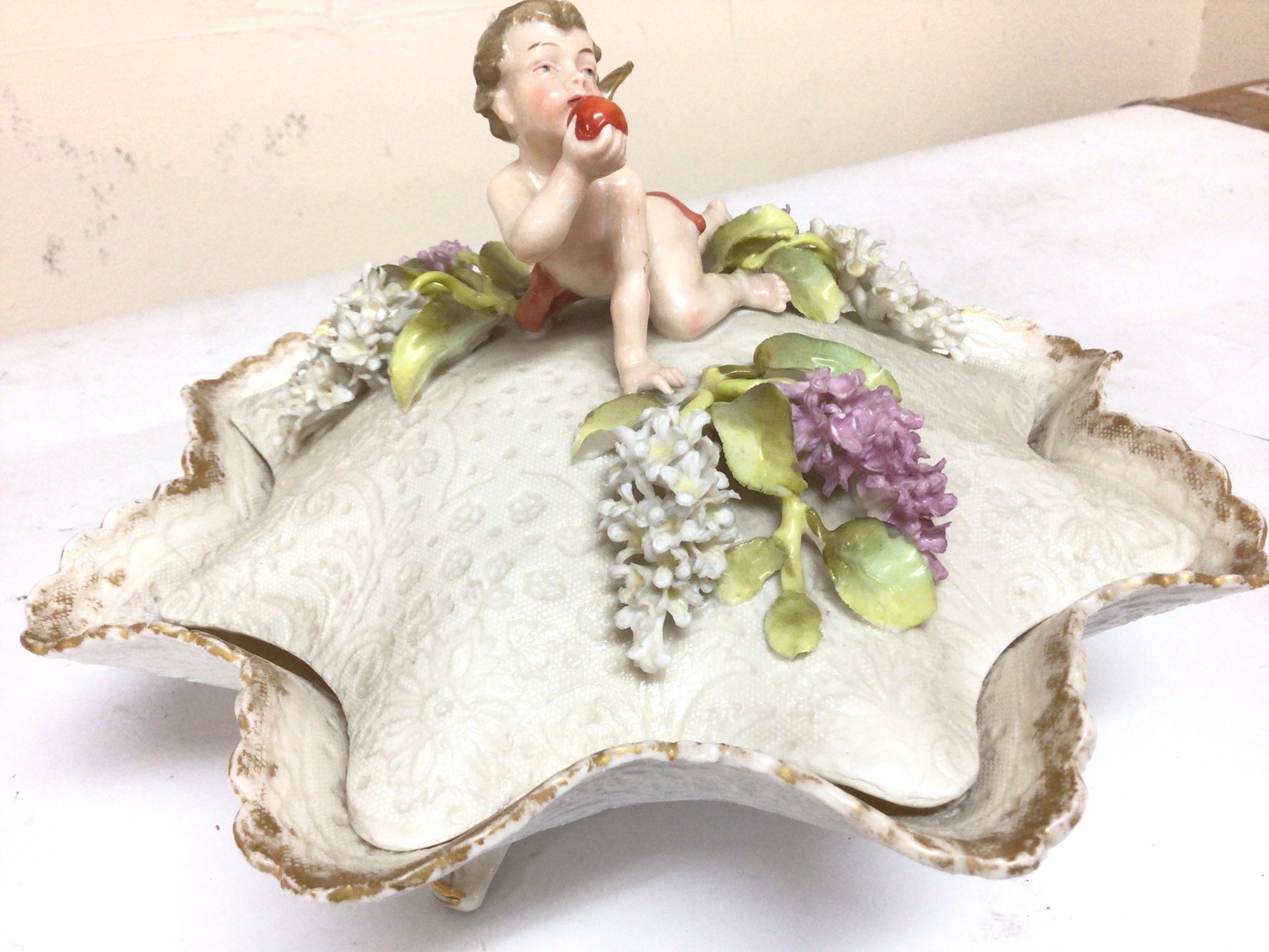  An Early 20th century porcelain dish and cover decorated with a raised cherub. 