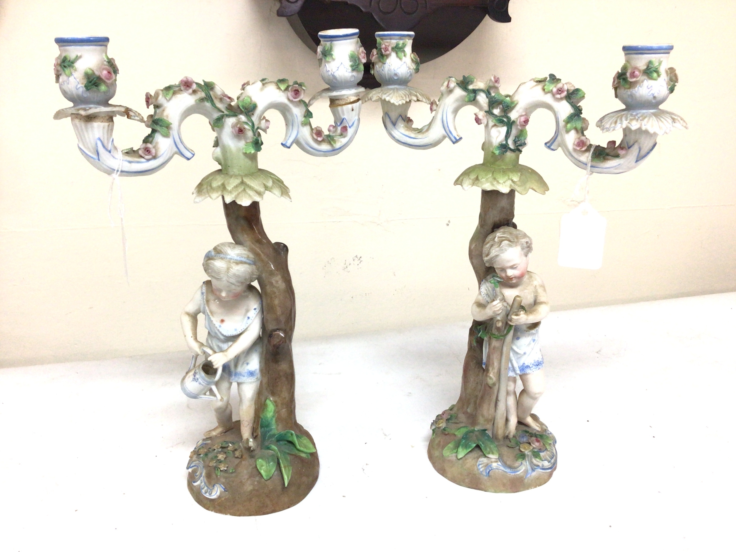  A pair of late 19th century German Porcelain candelabra of naturalistic form surmounted with figures of young children some damage. Height 33cm.