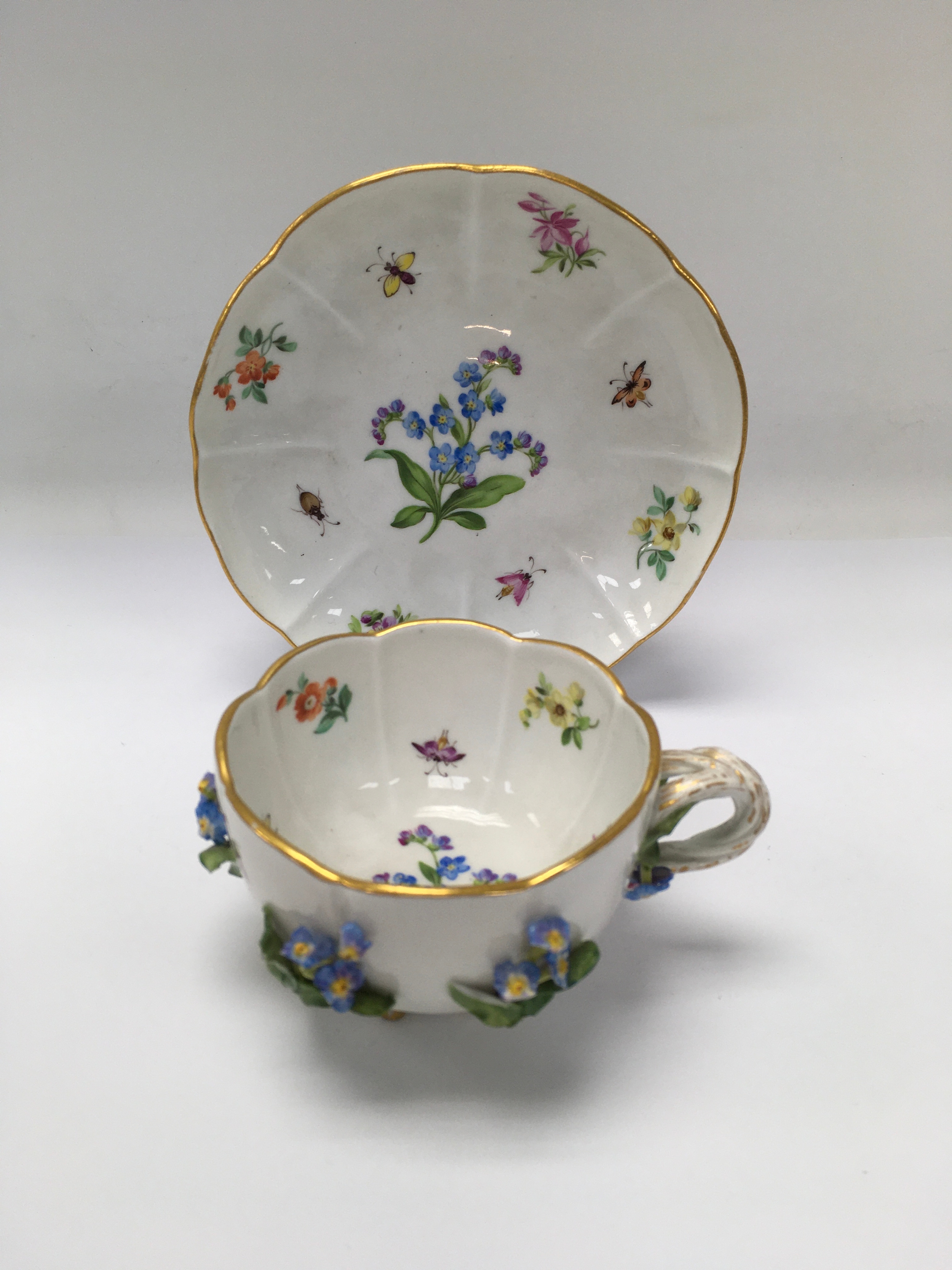 A hand painted Meissen cup and saucer of floral design, having applied decoration and gilded highlights. Saucer approx: 5.3cm