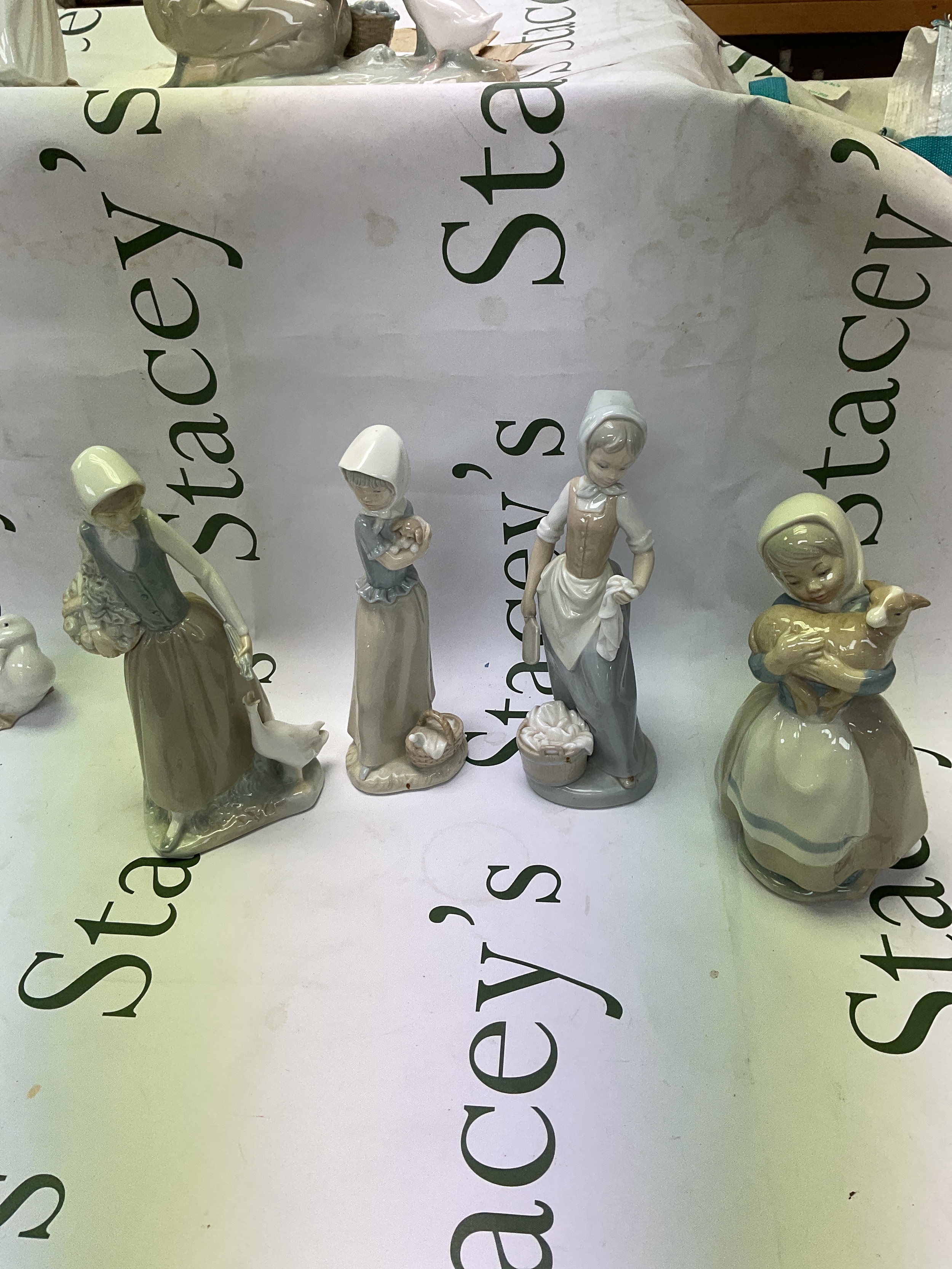 Four NAO figurines, girl with duck, girl with puppy, girl with lamb and girl washing.