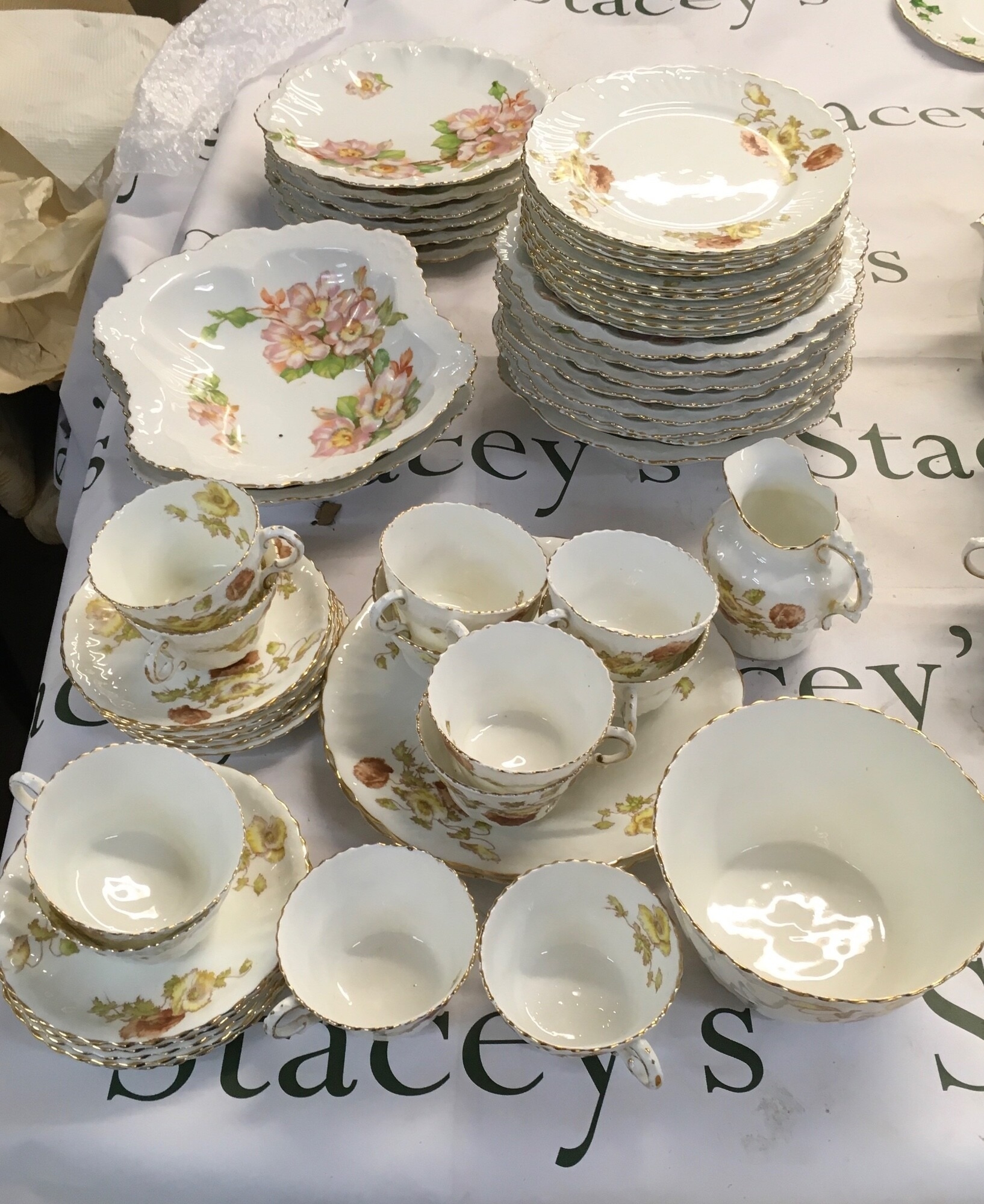 A collection of ceramic table ware consisting of delicate stylised flowers and leaves in warm autumn tones of amber. Also, this set contains dishes that have vibrant hand-coloured pink and yellow wild roses on trailing branches with bright green foliage NO RESERVE